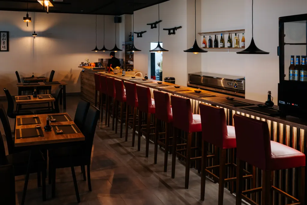 Bar sushi z czerwonymi hokerami w restauracji Daito Sushi